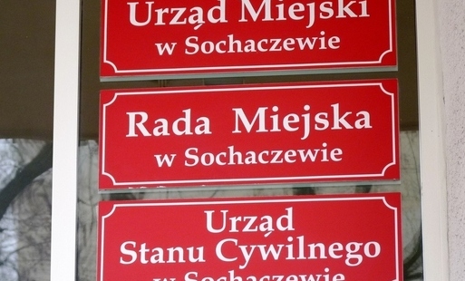 Czerwone tablice z nazwami instytucji, w tym Rady Miejskiej w Sochaczewie